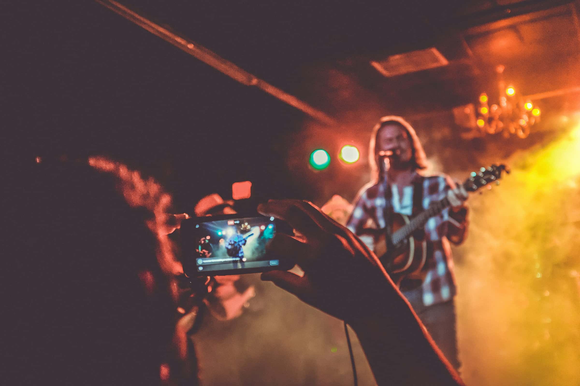 A phone recording a guitarist on stage
