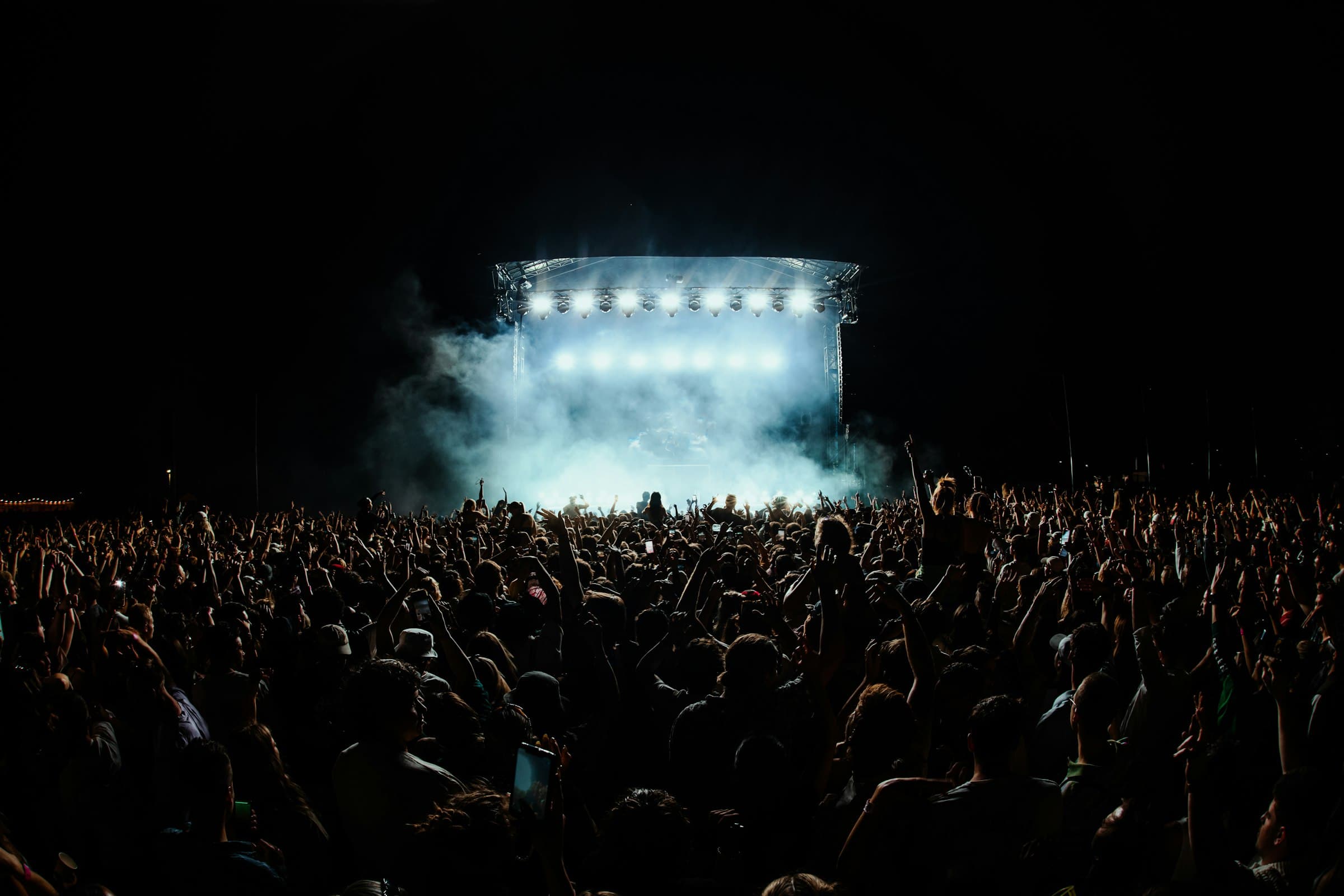 A large crowd in front of a smoke-filled stage
