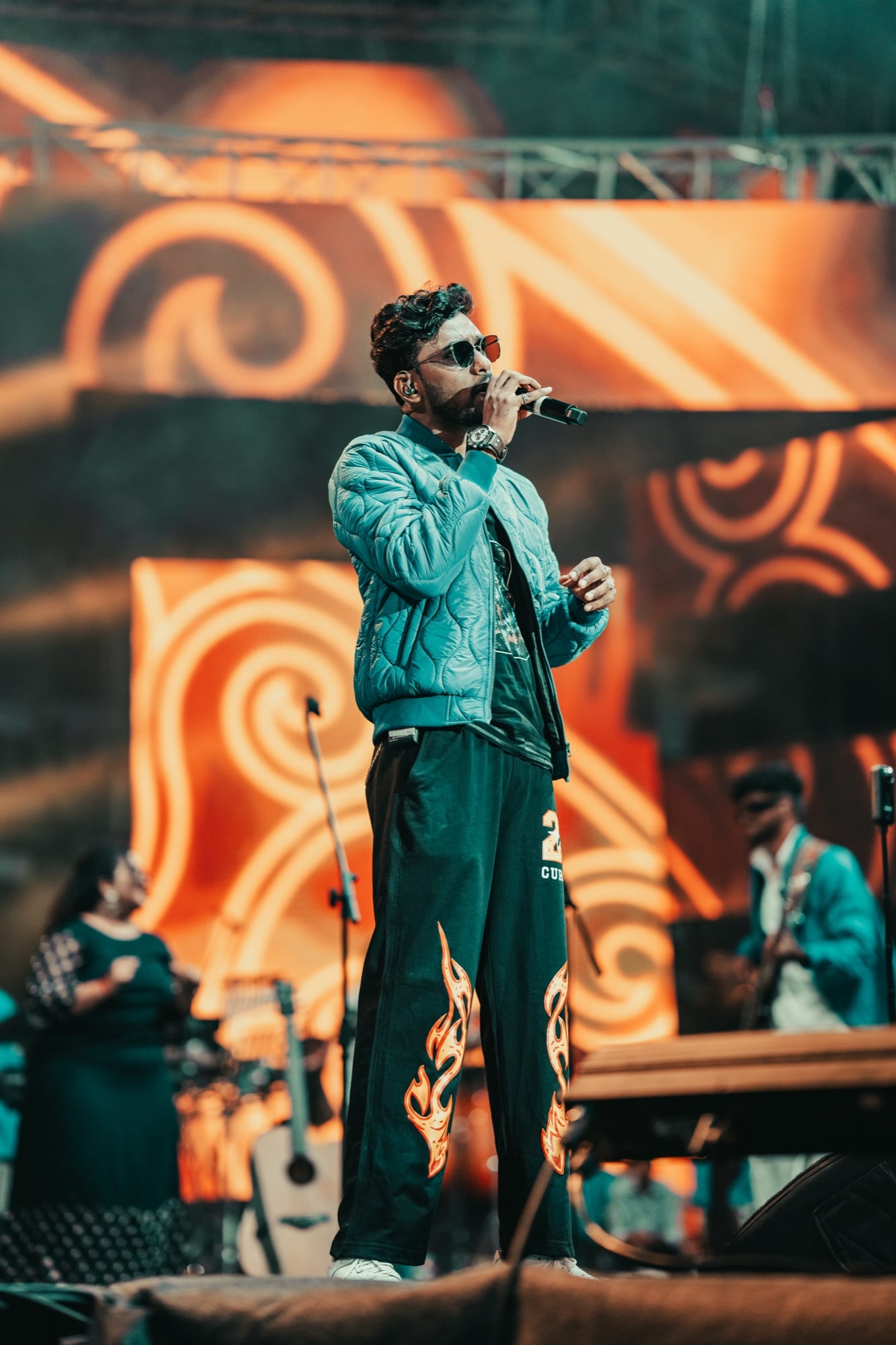 Vikram singing on stage in a teal quilted jacket
